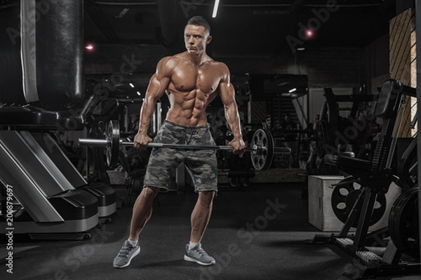 Fototapeta Handsome man with big muscles, posing at the camera in the gym