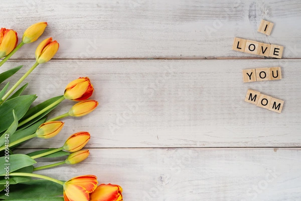 Fototapeta Yellow and red tulips on whitewashed wood with Mother's Day message