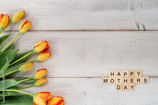 Fototapeta Yellow and red tulips on whitewashed wood with Mother's Day message