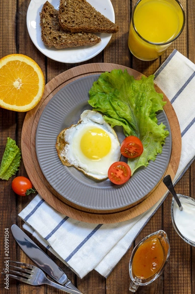 Fototapeta English Breakfast: fried egg, juice, cherry tomatoes, lettuce, grain bread, sauce, top view.