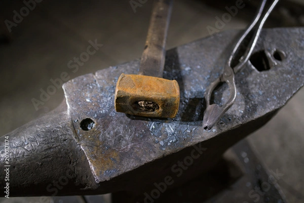Fototapeta Hammer and forceps lie on the anvil