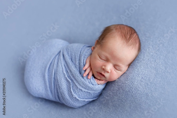 Obraz Photoshoot of a sleeping newborn boy on a blue background, wrapped in peanuts