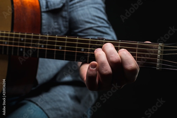 Fototapeta acoustic guitar in the hands of the guy on the whole frame
