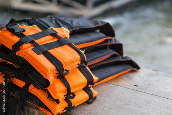 Fototapeta Closeup life jacket on wood table with river background, safety concept, selective focus
