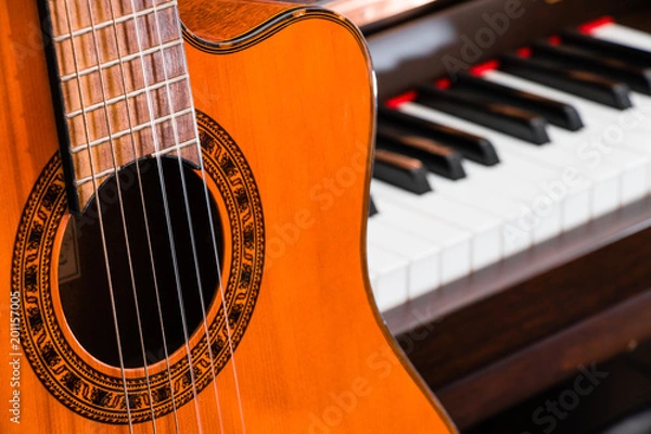 Fototapeta close up of classic guitar over grand piano keys for music background with copy space