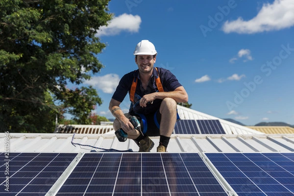 Fototapeta Solar panel technician with drill installing solar panels