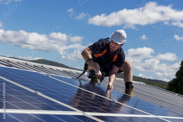 Obraz Solar panel technician with drill installing solar panels