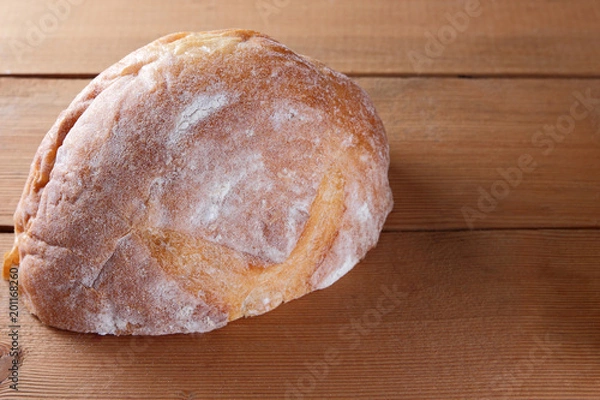 Fototapeta Sliced bread on a wooden background, two halves of wheat bread from a plate on pine boards, French dough for a designer, copy space, rustic style, wooden background, art