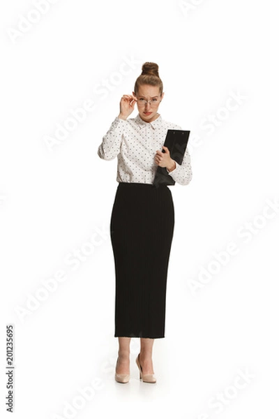 Fototapeta Full length portrait of a surprised female teacher holding a folder isolated against white background