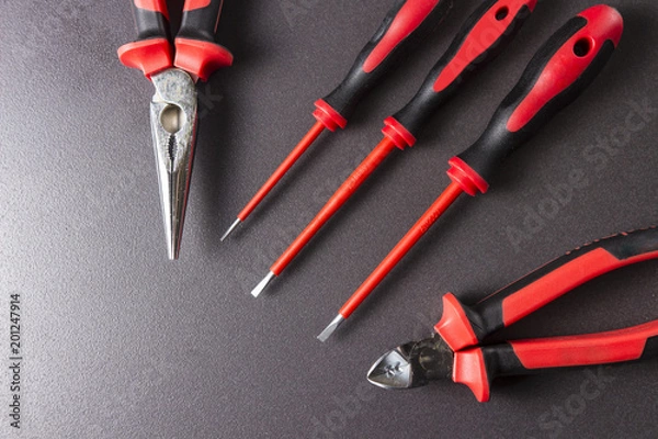 Fototapeta Tools electrician screwdrivers, pliers, platypuses on a black background.