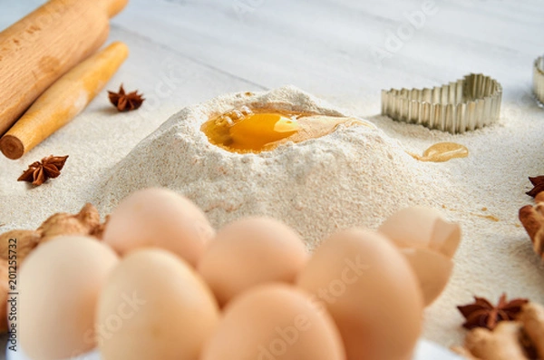 Fototapeta Ingredients for baking cake on the gray table: rolling pin, eggs, spices and bakewares. Baking background. Side view