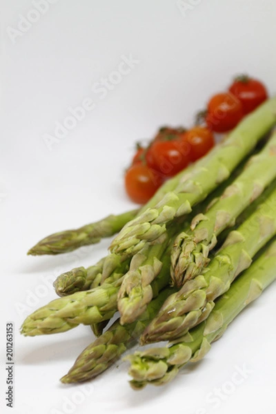 Fototapeta Green asparagus and red tomatoes on white background
