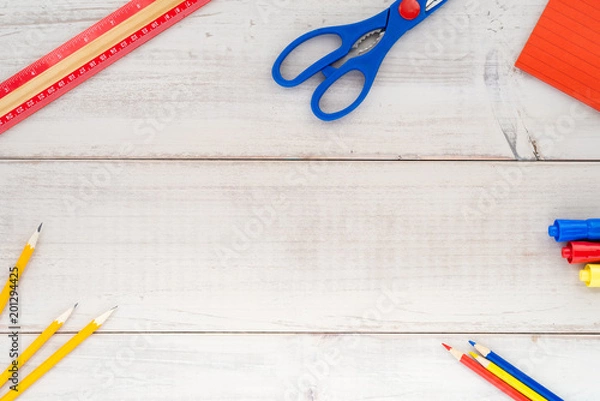Fototapeta Assorted school supplies in primary colors on a wood plank table