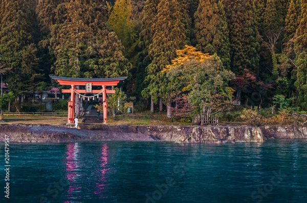 Fototapeta Red Torii of Gozanoishi Shrine at Lake Tazawa ko, Senboku, Akita, Japan. Japanese  characters on wooden sign on top of Torii gate is name of Shrine