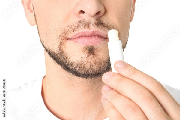 Fototapeta Man applying hygienic lip balm, on white background
