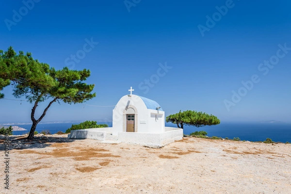Fototapeta Holy white and blue greek orthodox chruch chapel of agios mamas the holy mother shining at an empty place over the greek sea hidden by the mountains on the island of Kos, Dodecanese, Greece