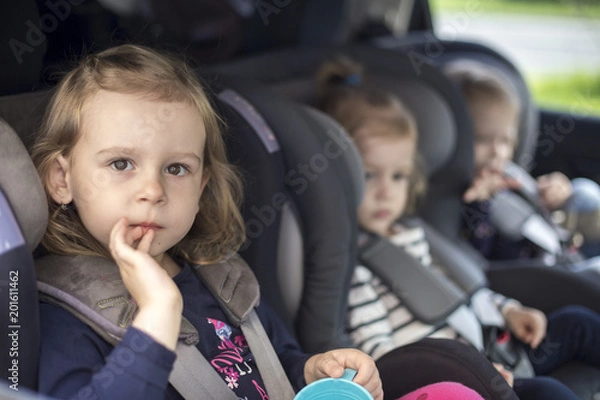 Fototapeta cute small sisters in car seats in the car