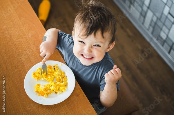 Fototapeta Dziecko w koszulce w kuchni, jedząc omlet, widelec