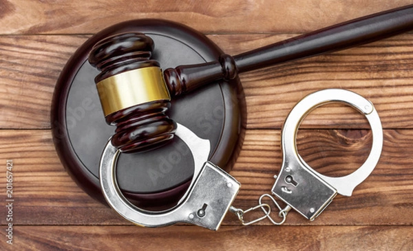 Obraz Gavel with stand and handcuffs on the wooden background. Top view.