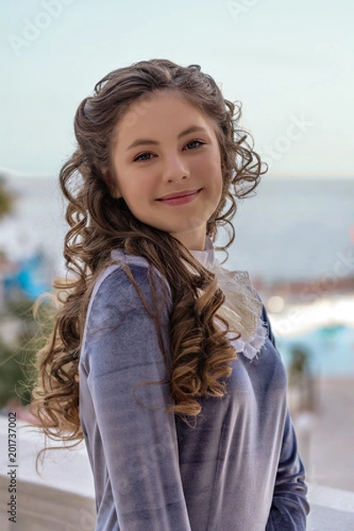 Fototapeta portrait of a smiling sly naughty girl with curlers in an old retro dress