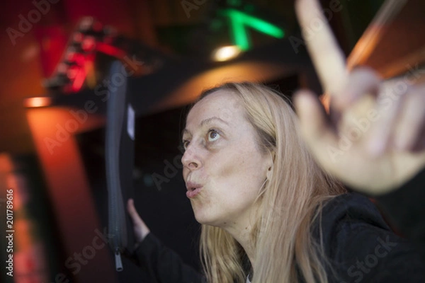 Fototapeta Mujer contenta con una funda de ordenador o documentos celebrando algo. Noche, luces de pub-discoteca al fondo. Fiesta, vida  nocturna