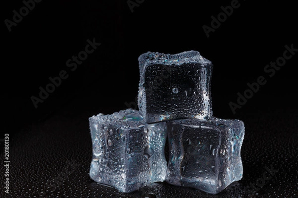 Fototapeta Cubes of clear ice on a black table.