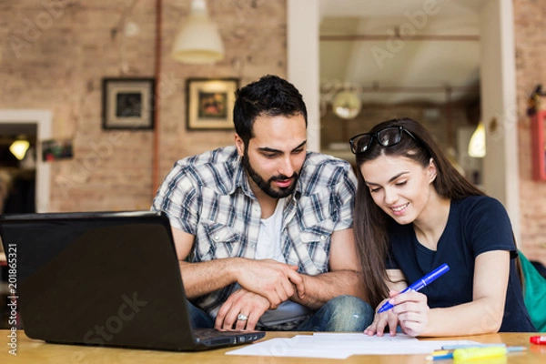 Fototapeta Couple of freelancers working with laptop in modern stylish coworking office, teamwork success concept
