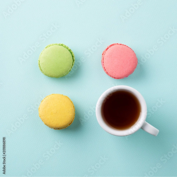 Obraz Cup of tea with colorful macarons on light blue background