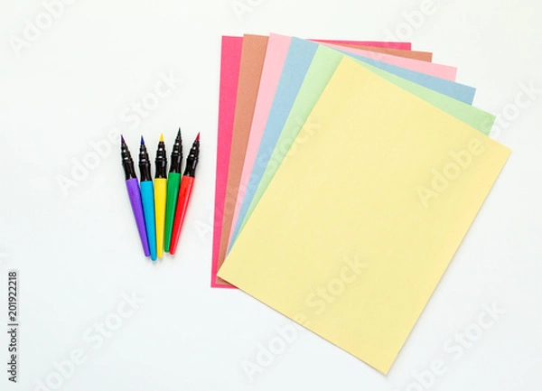 Obraz brightly colored paint pens with fanned out multicolored construction paper isolated on white