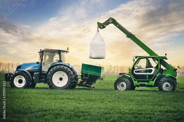 Obraz fertilizers are carried in a sacks on the tractor trailer in the field in the spring