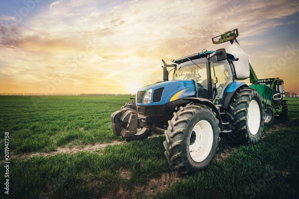 Obraz a tractor with a sack of fertilizer moves along the field in the spring