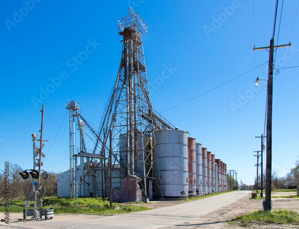 Fototapeta grain elevators next to a railroad crossing