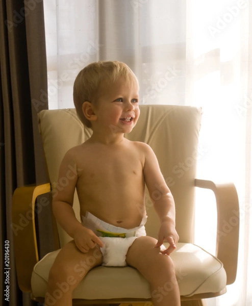 Fototapeta A portrait of a smiling one-year-old boy wearing only a diaper
