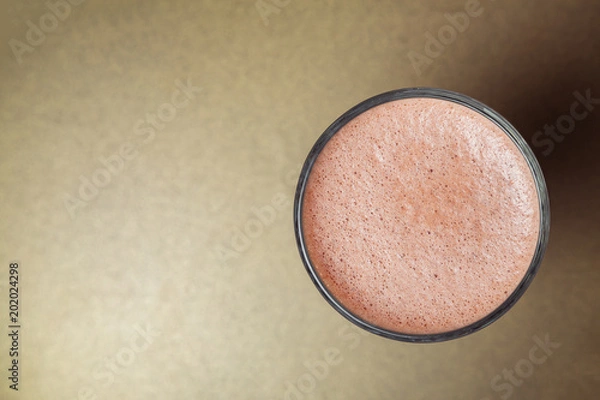 Fototapeta Glass cup of cacao with cream close-up on gold background. View from above