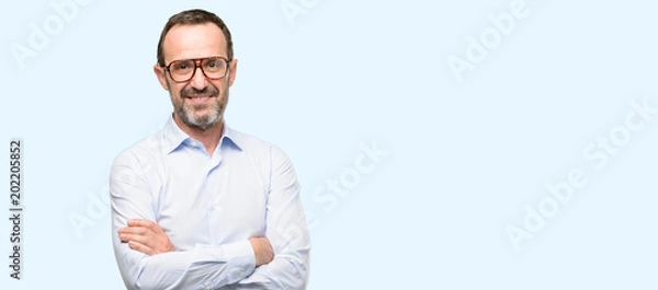 Fototapeta Middle age man with glasses with crossed arms confident and happy with a big natural smile laughing isolated over blue background
