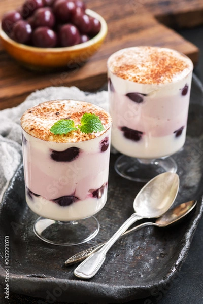 Fototapeta Dessert yoghurt with a cherry in glasses on a ceramic rustic tray. Selective focus.Canned cherry
