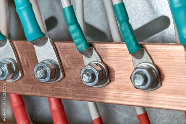 Fototapeta Electric bus bars connected to it by wires or cables. The cables are connected with cable lugs and nuts bolts. Accumulation and interlacing of wires or cables in the electrical Cabinet.