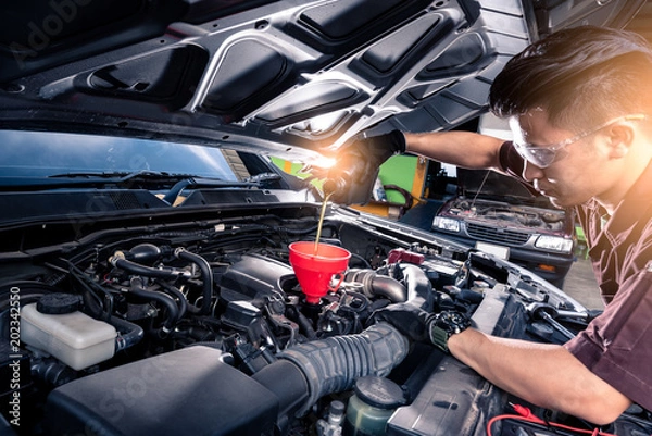 Obraz the wide angle image of the technician filling a new lubricant in the car's engine. the concept of automotive, repairing, mechanical, vehicle and technology.