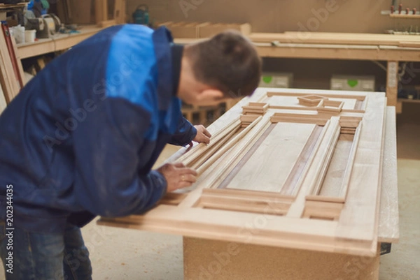 Obraz a carpenter makes a door