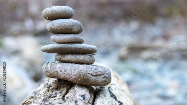 Obraz A stack of rocks with on a bright wooden log