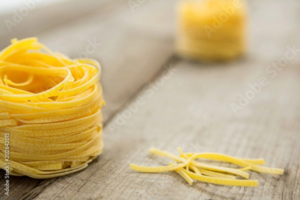Fototapeta Tagliatelle pasta on wooden surface