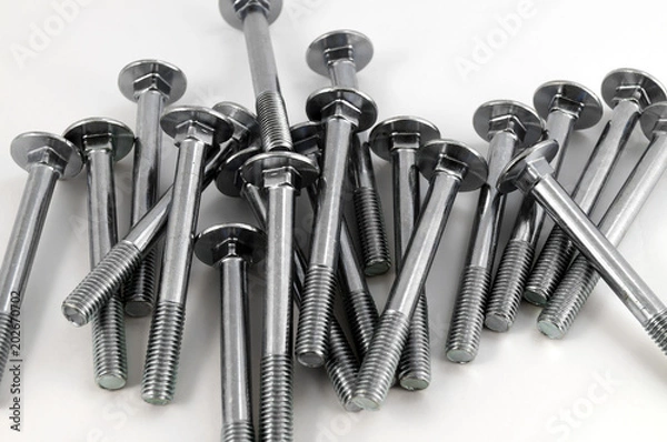 Fototapeta Heap of metal bolts of chrome steel with a round head and incomplete thread on a white background.