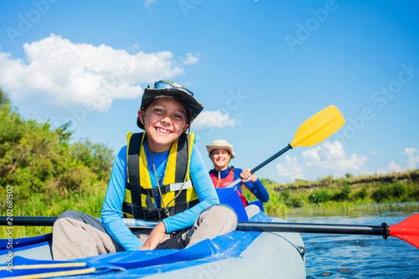 Fototapeta Happy boy kayaking on the river on a sunny day during summer vacation