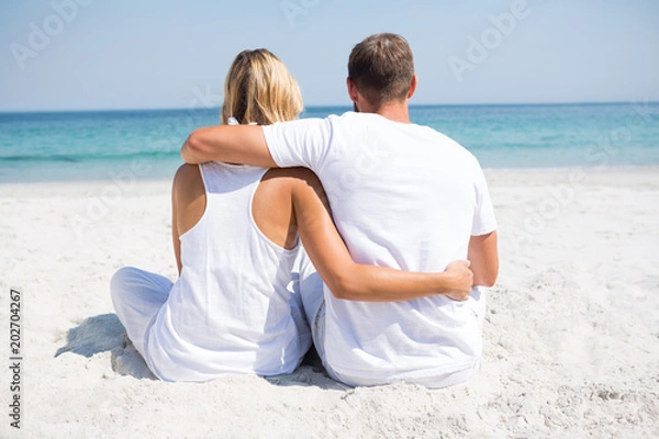 Fototapeta Rear view of couple relaxing at beach