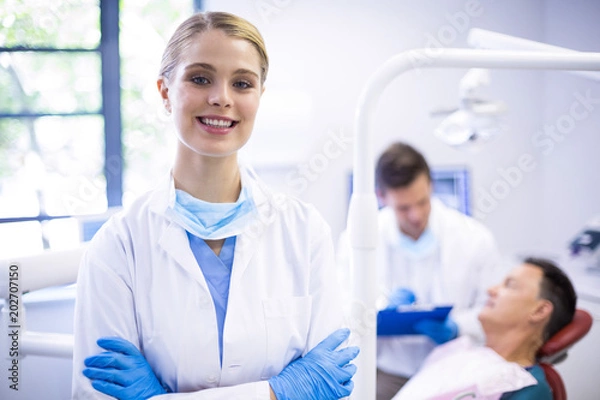 Fototapeta Portrait of smiling dentist standing  with arms crossed