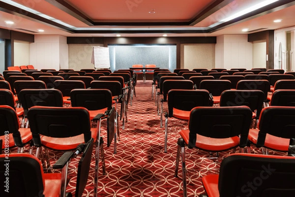 Fototapeta rzędy czerwonych krzeseł w pustej sali konferencyjnej