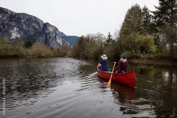 Fototapeta Couple adventurous friends canoeing on the lake with Chief Mountain in the background. Taken in Squamish North of Vancouver, British Columbia, Canada.