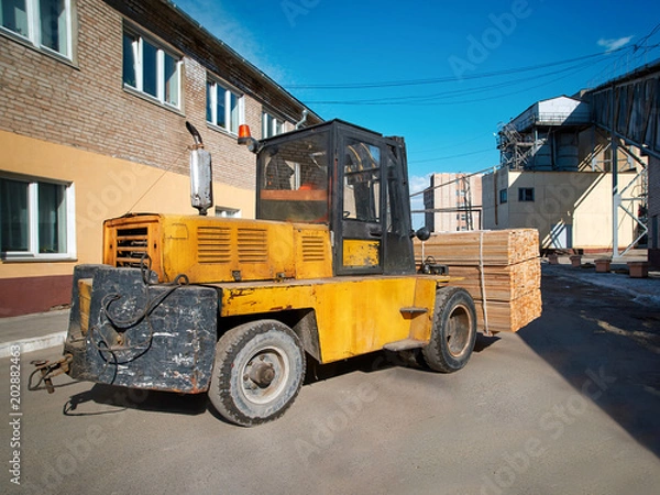 Obraz Forklift transporting new wood boards in stacks at production yard. Boards for furniture materials, wood material warehouse	