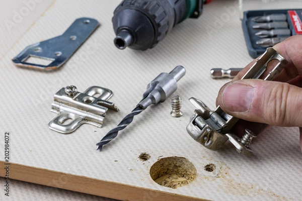 Fototapeta Assembly of hinges in a carpentry workshop. Joinery accessories in a carpentry workshop on a wooden table.