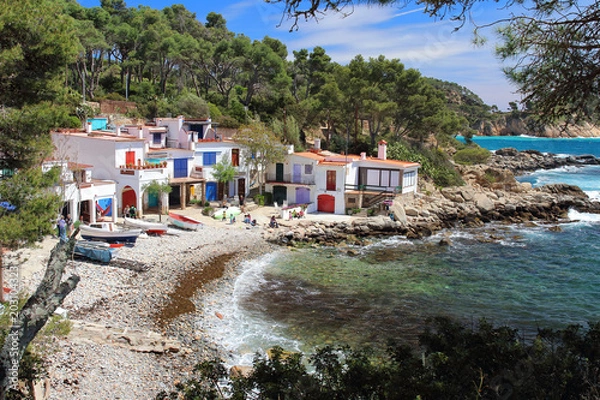 Fototapeta Main view of cala s'Alguer, a lovely beach surrounded by traditional fishermen's white buildings with colorful doors and windows, Palamos, Costa Brava, Spain.